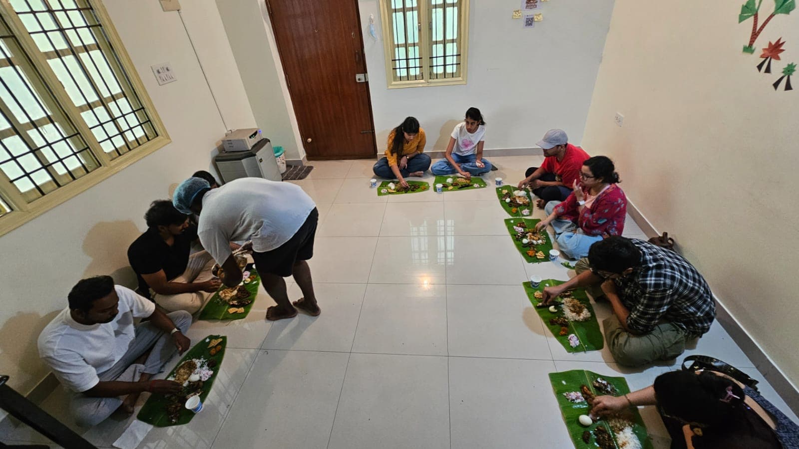 Banana leaves laid out on the floor, guests sitting around eating